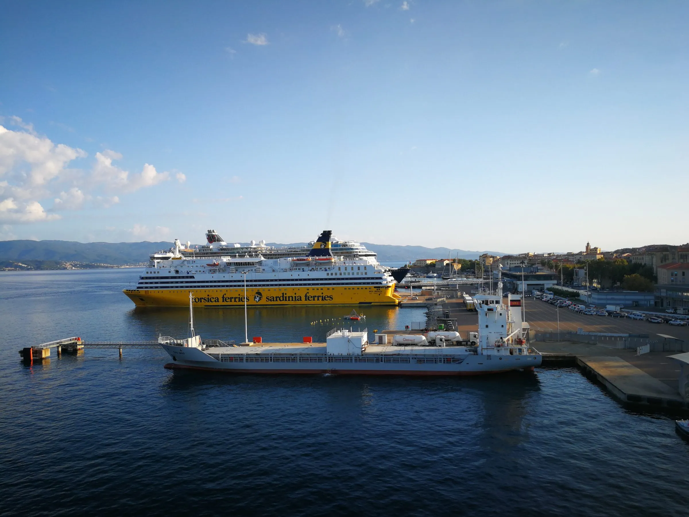 Hafen von Ajaccio mit einer gelben Fähre von Corsica Ferries und einem Frachtschiff am Kai
